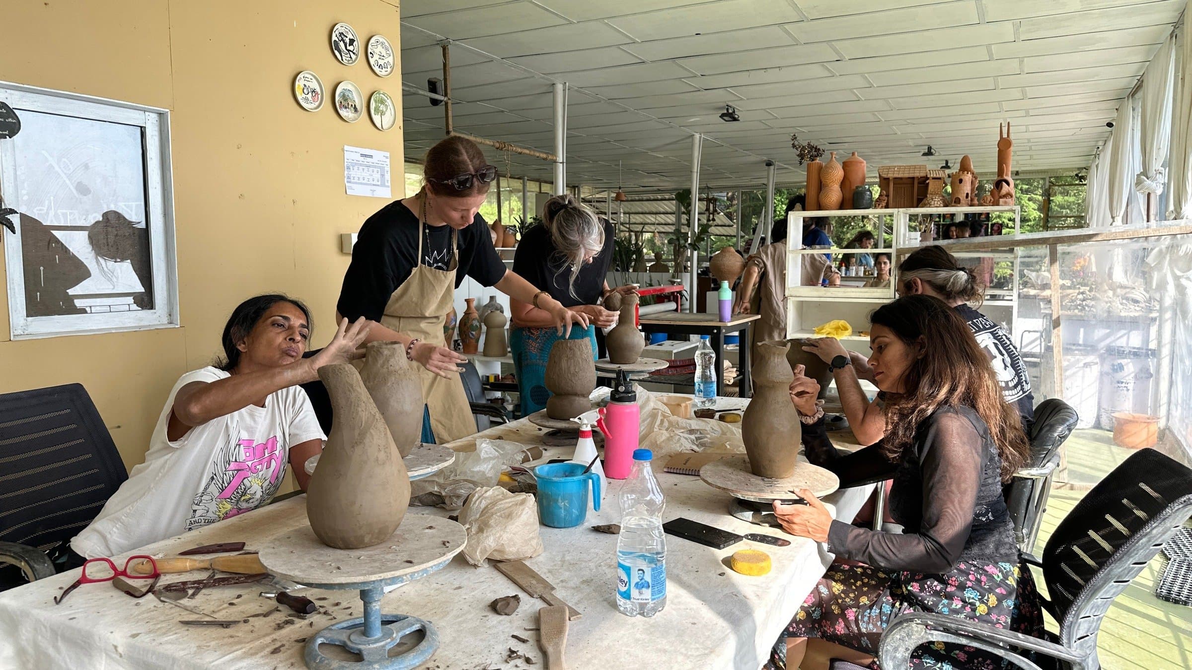 Participants shaping clay together during a Dharamkot Studio retreat.