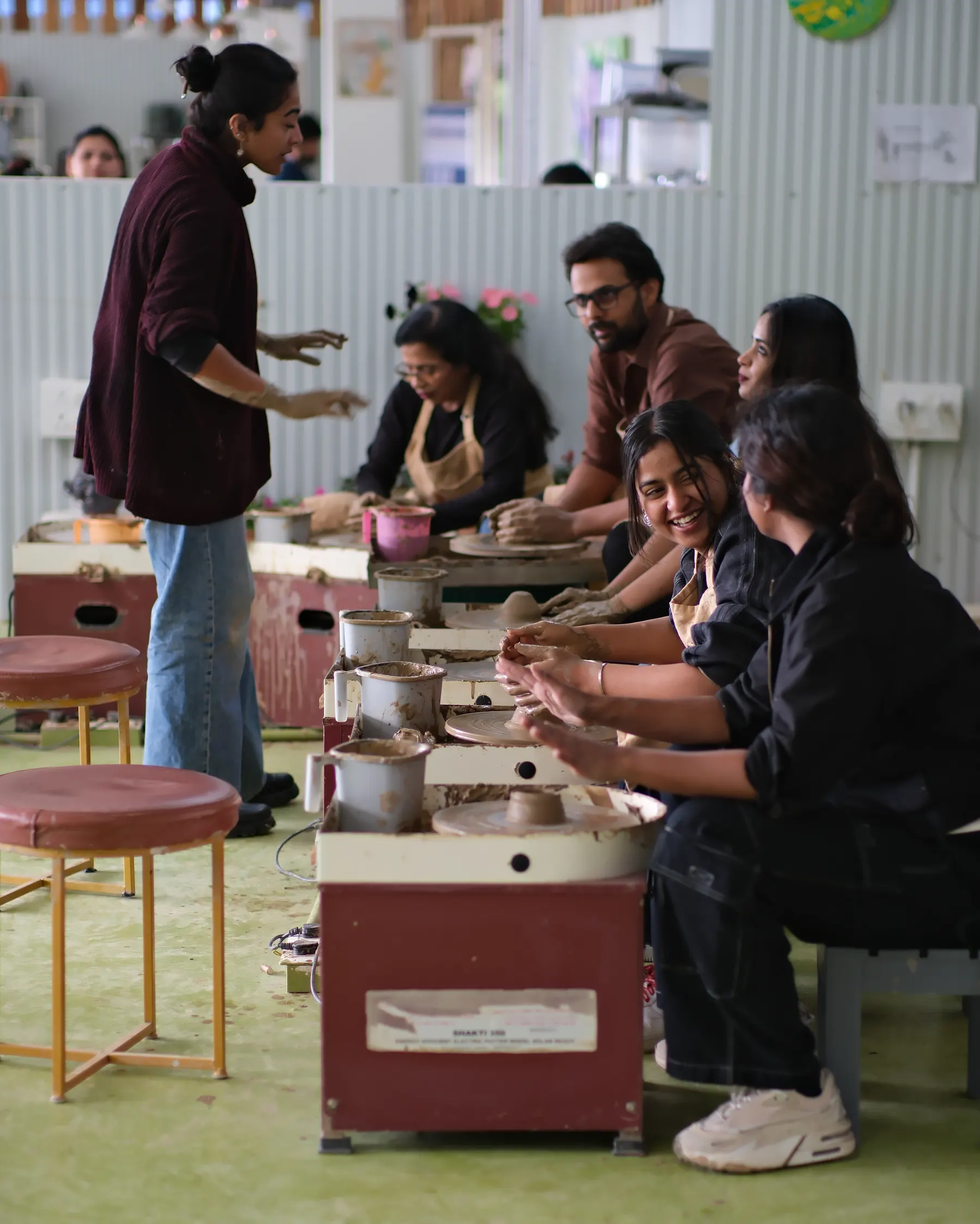 Pottery instructor supporting students at the wheel in Dharamkot Studio.