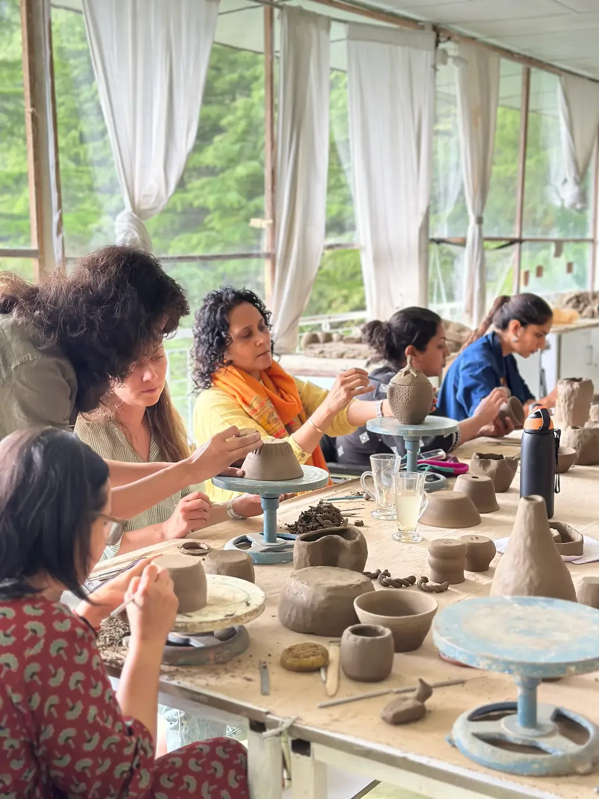 Pottery retreat participants practicing clay work in a bright mountain studio in Himachal Pradesh.