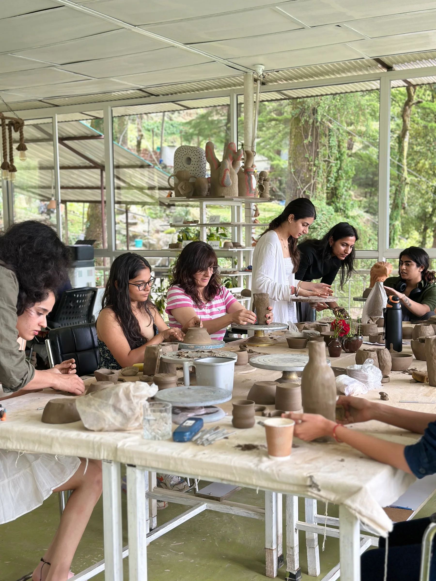 Retreat participants handbuilding clay together around a shared studio table in Himachal Pradesh.