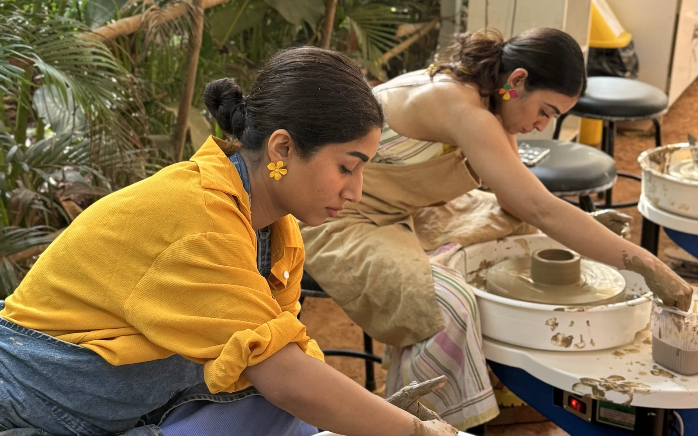 Two retreat participants practicing wheel throwing together in the open Goa pottery studio.