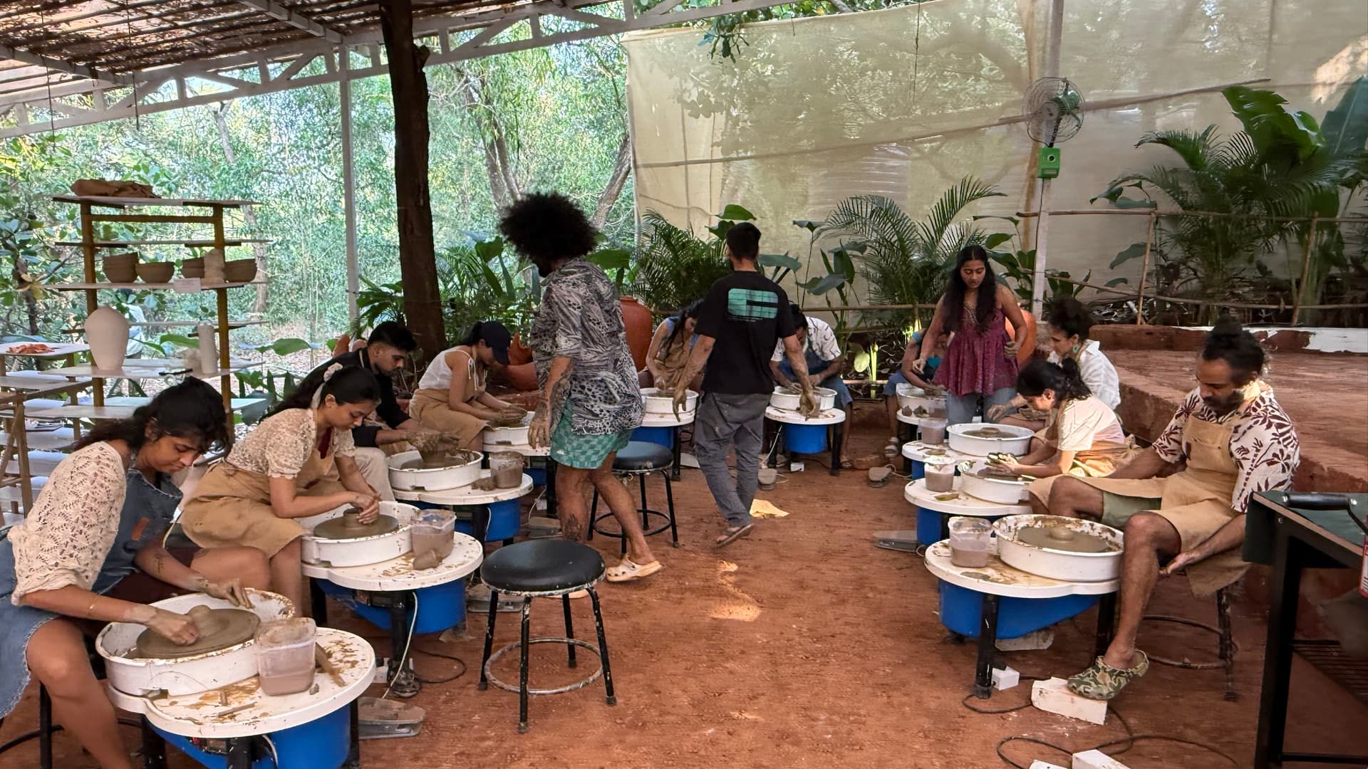 Participants practicing pottery wheel throwing together in the open-air Goa studio at Dharamkot Studio.