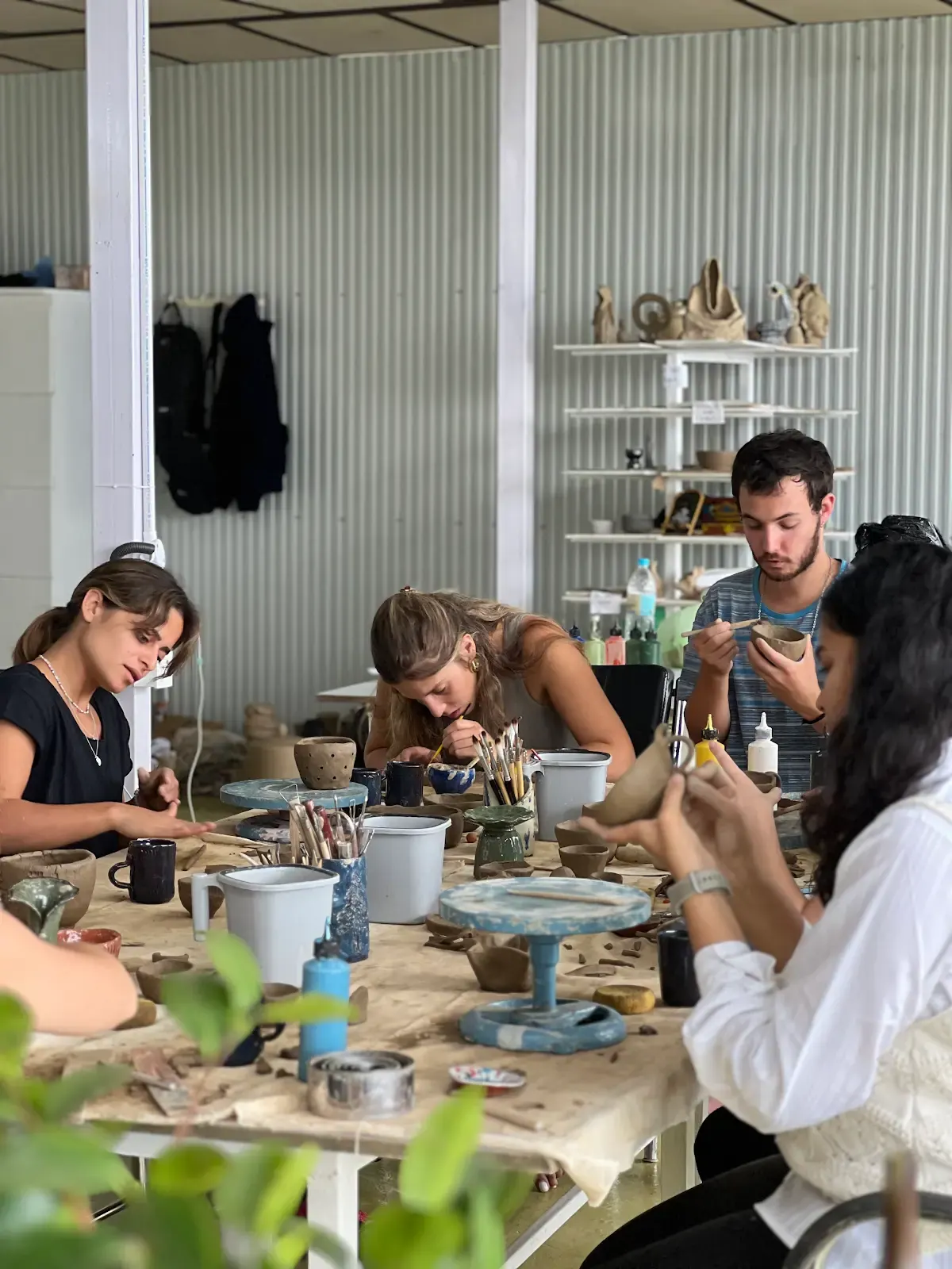 Small group refining hand-built pottery together during the Sculpt & Shape workshop in Himachal Pradesh.